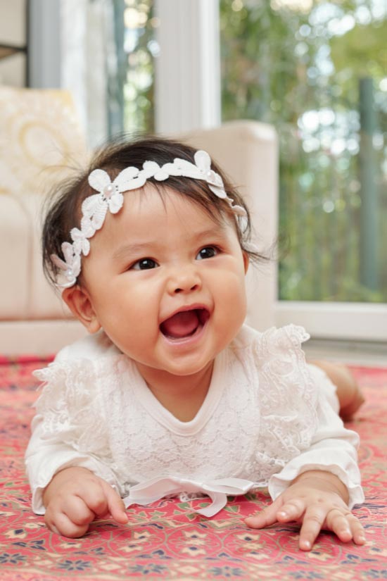 Baby girl on the floor, smiling.